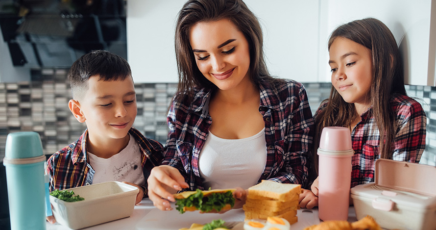 A Hispanic mother prepares a meal with her son and daughter. 