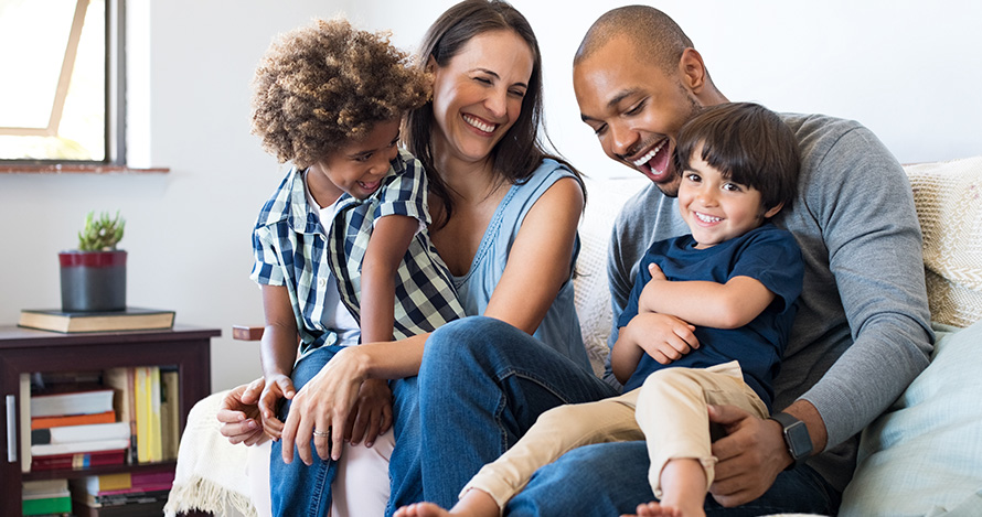 A mixed race family with adopted children has fun at home. 