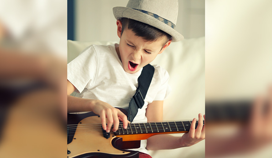 Little boy singing and playing a guitar.