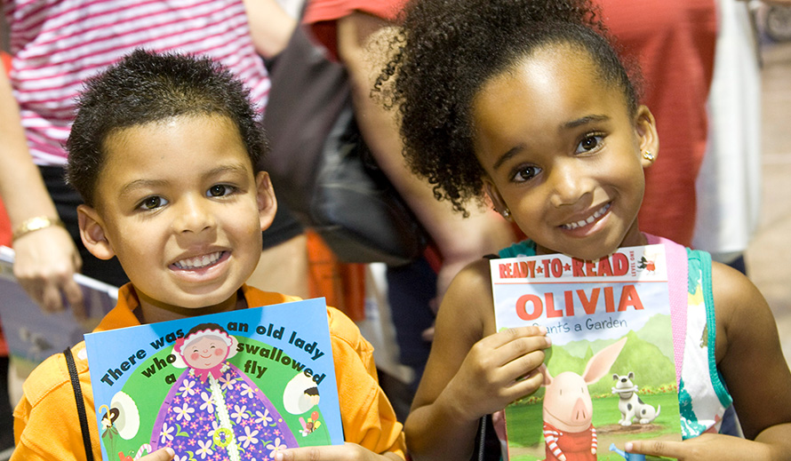 Niño y niña sonriente, cada uno sosteniendo un libro.