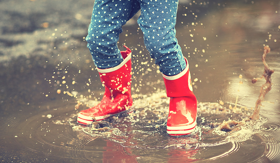 Botas de lluvia infantiles salpicando en un charco