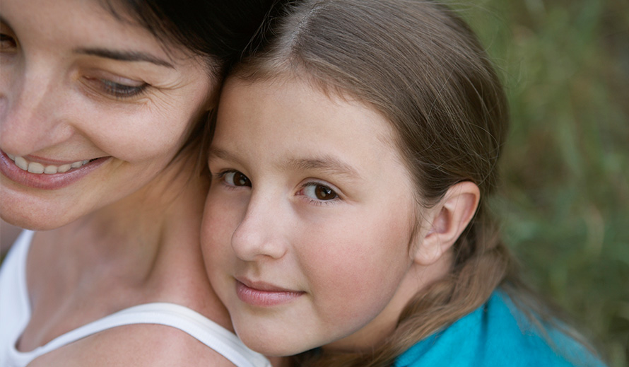 Smiling mom being hugged by her young daughter