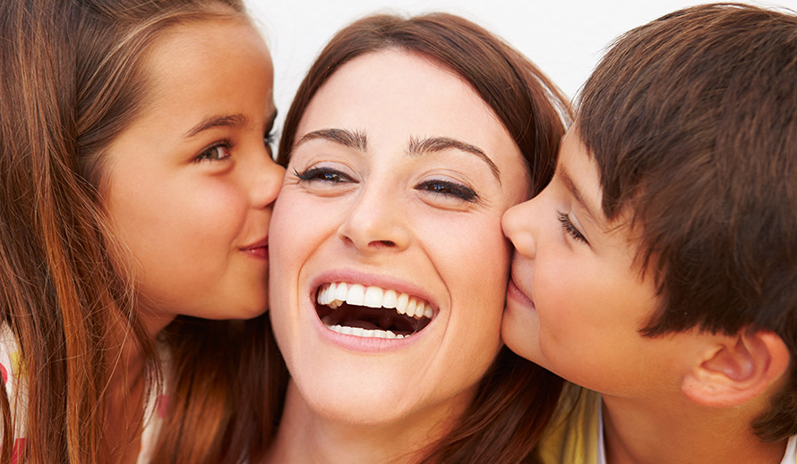 Happy mom being kissed on either cheek by her children