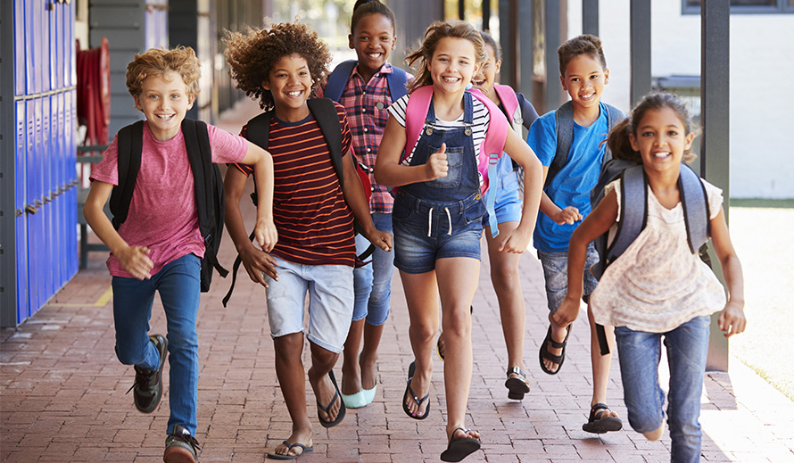 Happy children running through a school hallway.