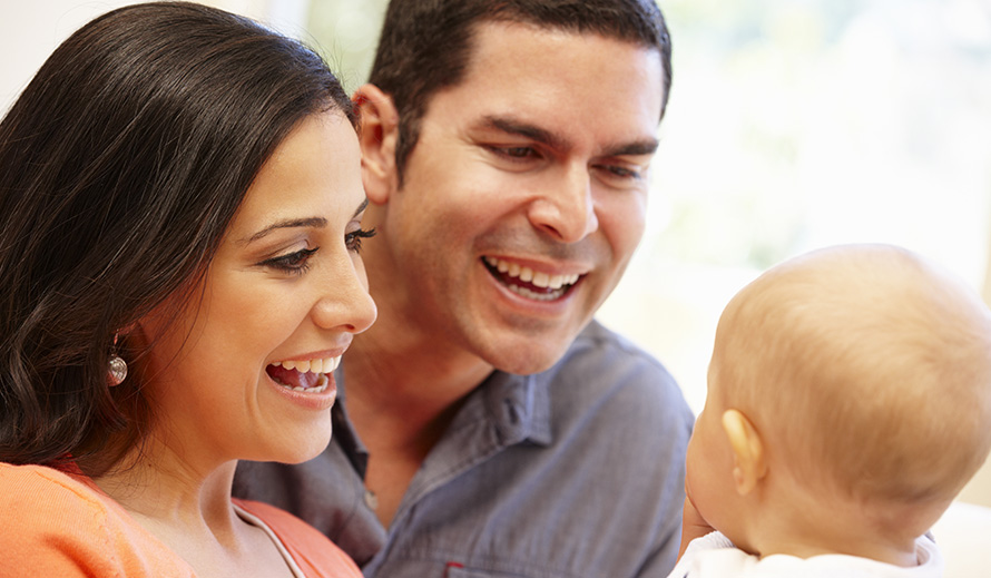 Una mamá y un papá felices hablándole a su bebé.