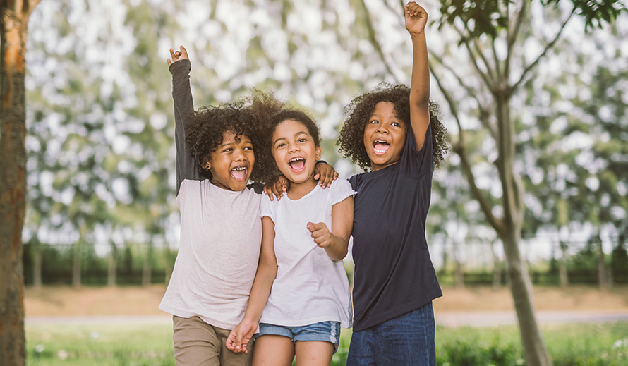 Trío de niñas felices, con los brazos en alto triunfantes.