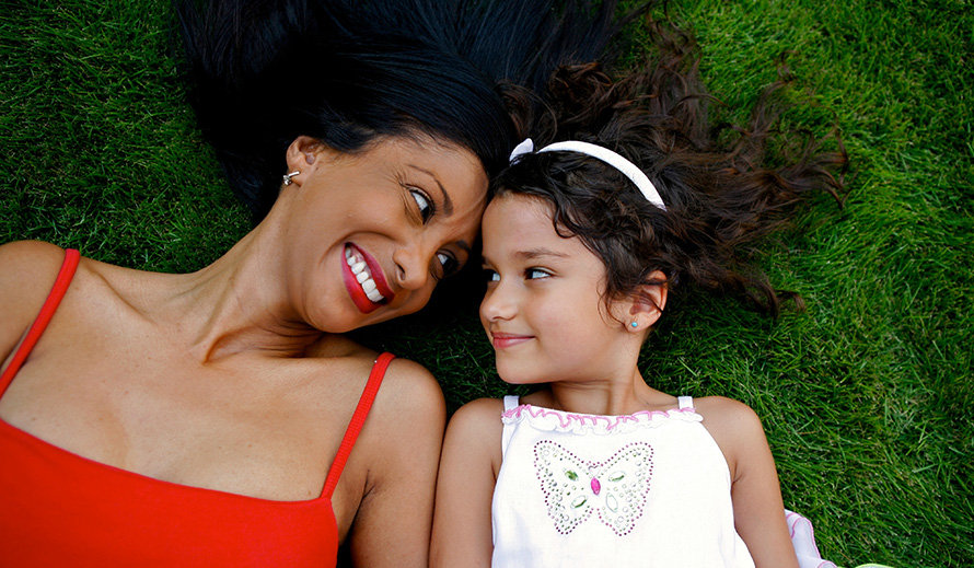 Mother and daughter laying on the grass.