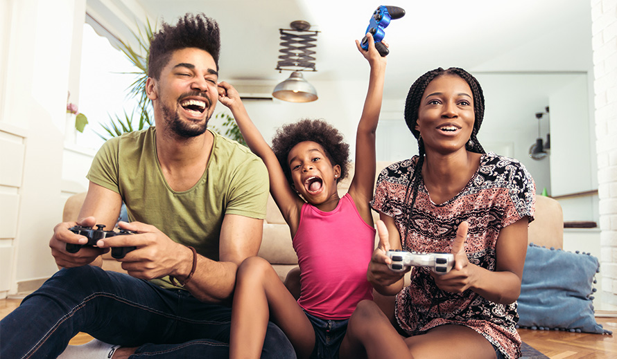 Padres jugando videojuegos con su hija.