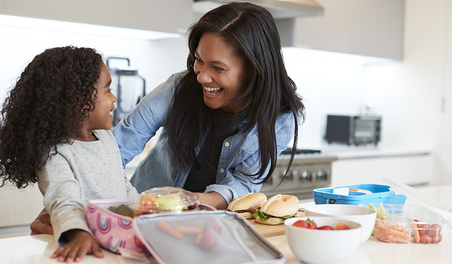 Una mamá y su hija preparan juntas el almuerzo escolar.