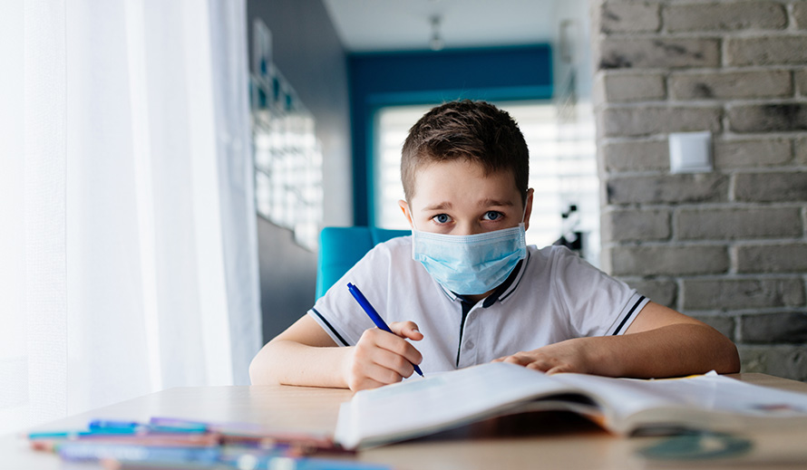 A young boy does schoolwork from home. 