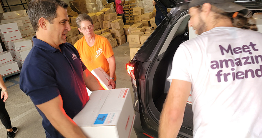 El presidente y director ejecutivo de Children's Trust, James Haj, carga libros durante un evento de distribución en el verano.