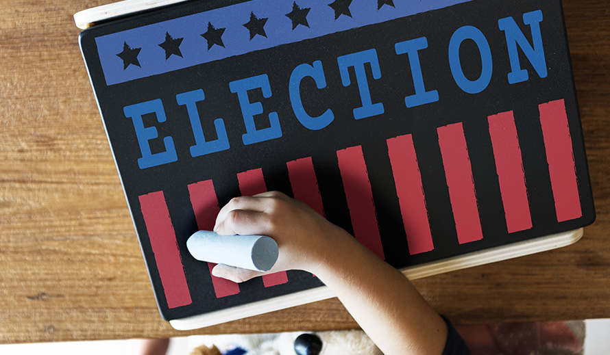 Child beginning to write with chalk on election sign