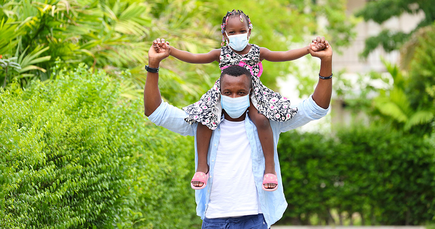 Una niña afroamericana se sienta sobre los hombros de su padre.