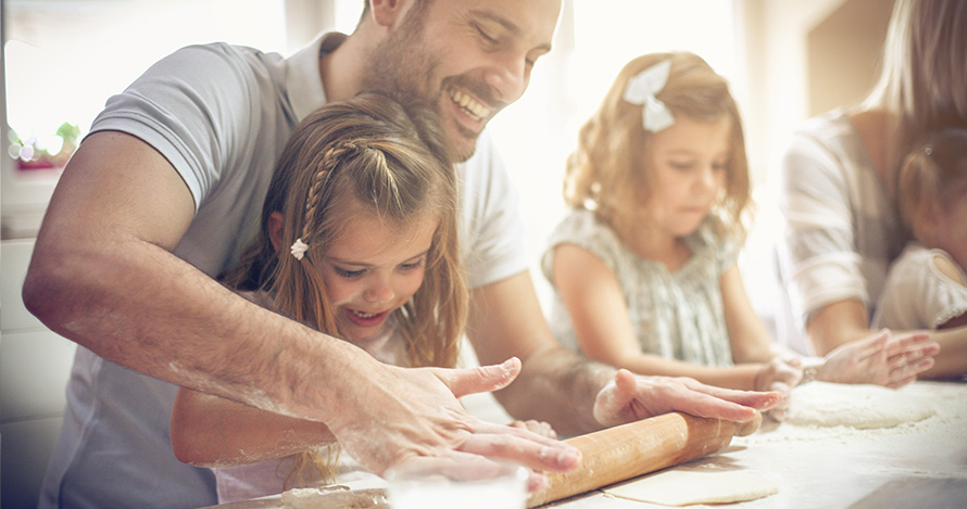 Un padre prepara una comida con sus hijos.