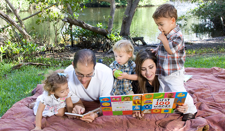 Familia leyendo sobre un manto en el parque.