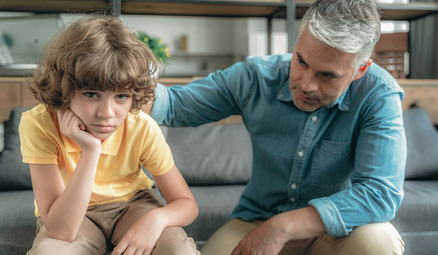 Father comforts boy in emotional distress. 