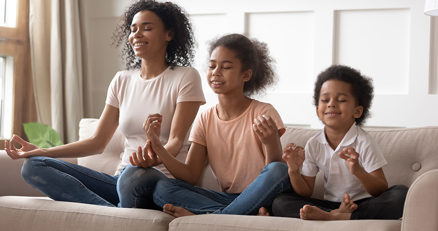 Una madre afroamericana medita con sus dos hijos pequeños.