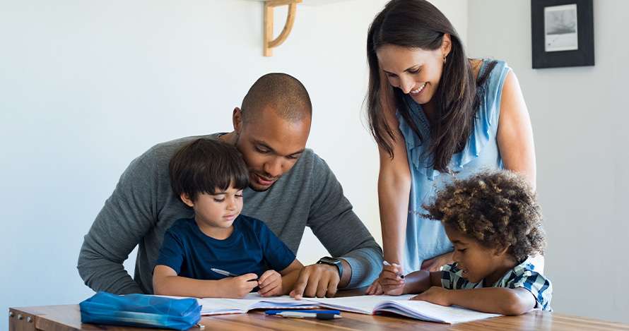 Una familia diversa se sienta alrededor de una mesa leyendo.