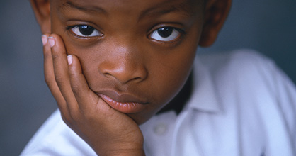 Young boy with his chin in his hand, sporting a dubious look on his face