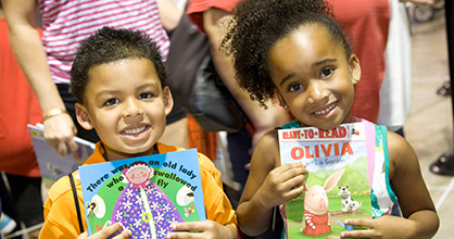 Niño y niña sonriente, cada uno sosteniendo un libro.