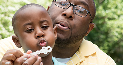 Father and young son blowing bubbles in the park.