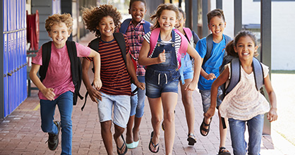 Happy children running through a school hallway.