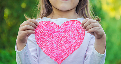 Jovencita sosteniendo un corazón del amor en cartulina.