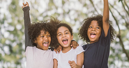 Trío de niñas felices, con los brazos en alto triunfantes.