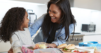 A mother and daughter prepare school lunch together.