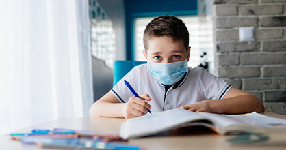 A young boy does schoolwork from home. 