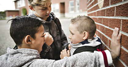 A couple of older kids gang up on a younger child.