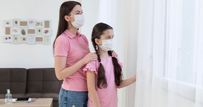  Madre e hija miran por la ventana durante la pandemia.