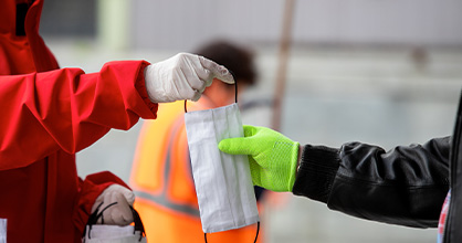 A service provider hands a protective mask to a resident.