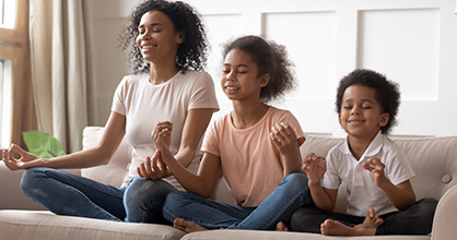 An African American mother meditates with her two young children.